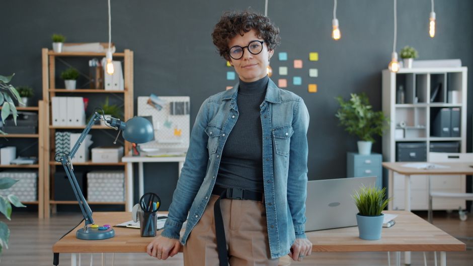 Pessoa confiante em um escritório moderno com plantas e material de escritório.