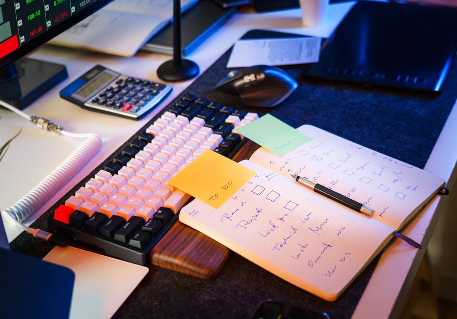 Mesa de escritório moderna com teclado, caderno e lista de tarefas para aumentar a produtividade.