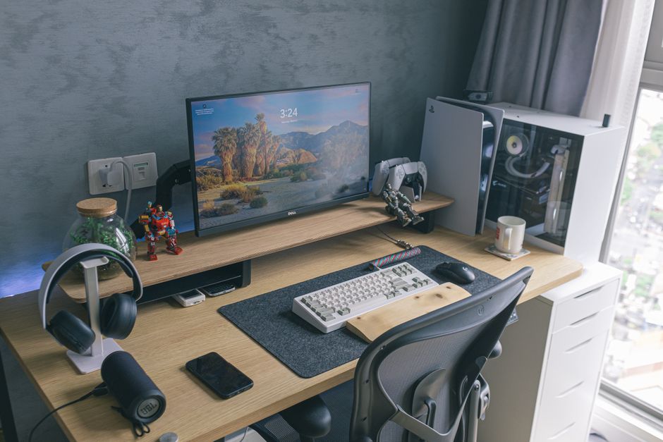 Um escritório em casa elegante com um console de videogame, monitor, teclado e acessórios de mesa, ideal para entusiastas de tecnologia.