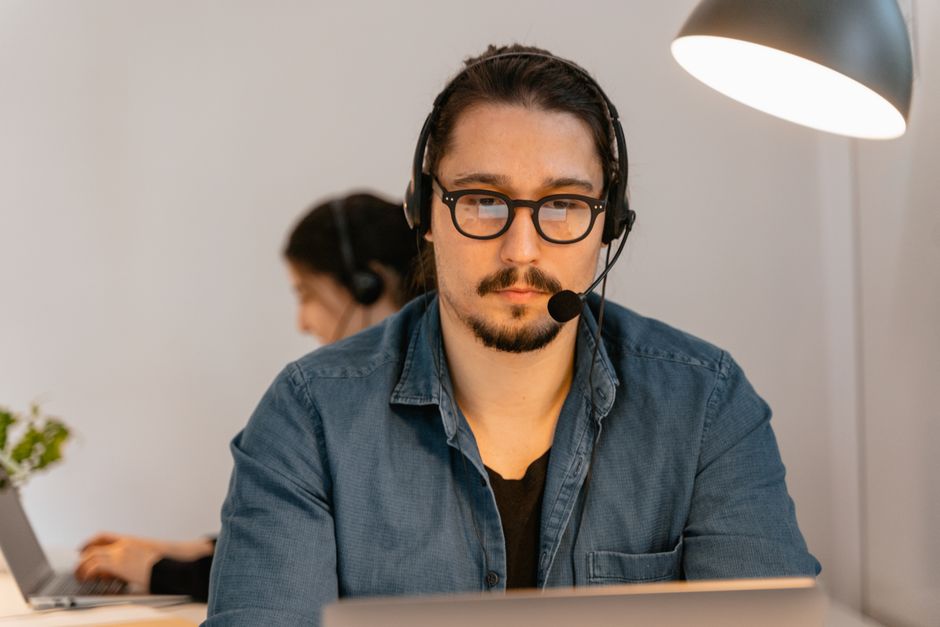 Um agente de call center usando fones de ouvido, trabalhando intensamente em sua mesa em um ambiente de escritório moderno.